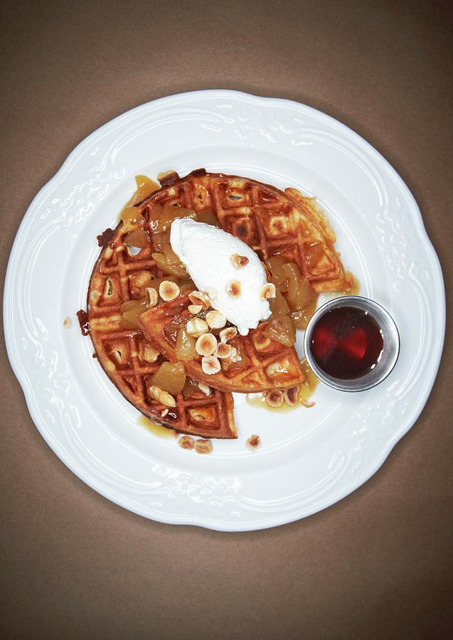 Hazelnut Waffle With Poached Fruit And Chopped Roasted Hazelnuts On A White Plate; Side Of Maple Syrup Photograph by Rannells, Greg