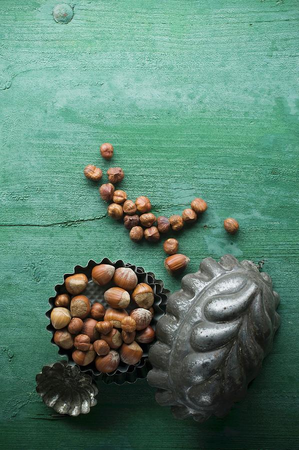 Hazelnuts, Shelled And Unshelled, In A Baking Tin On A Rustic Wooden Surface Photograph by Achim Sass