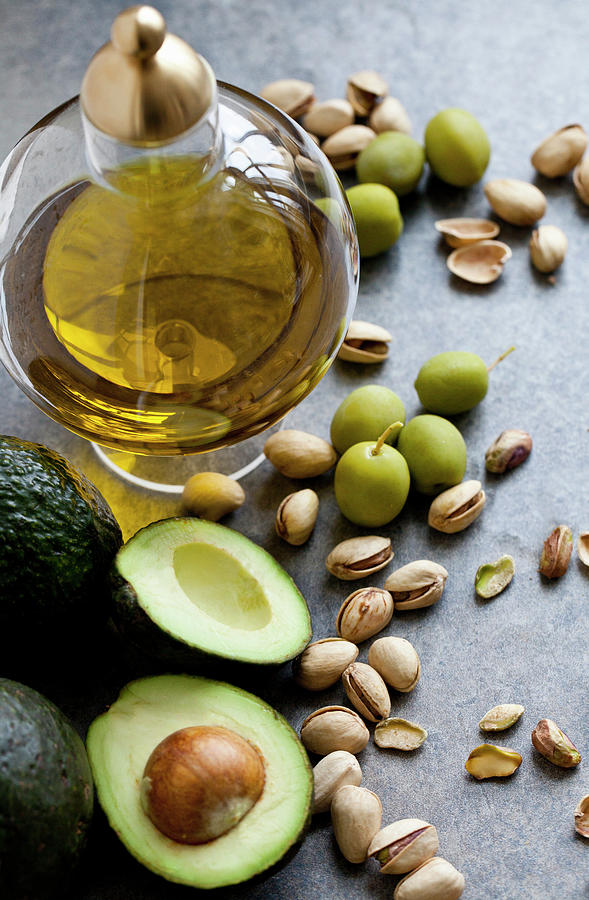 Healthy Fats - A Jar Of Olive Oil, With Olives, Pistachio Nuts And Avocados Sitting Beside Photograph by Ryla Campbell