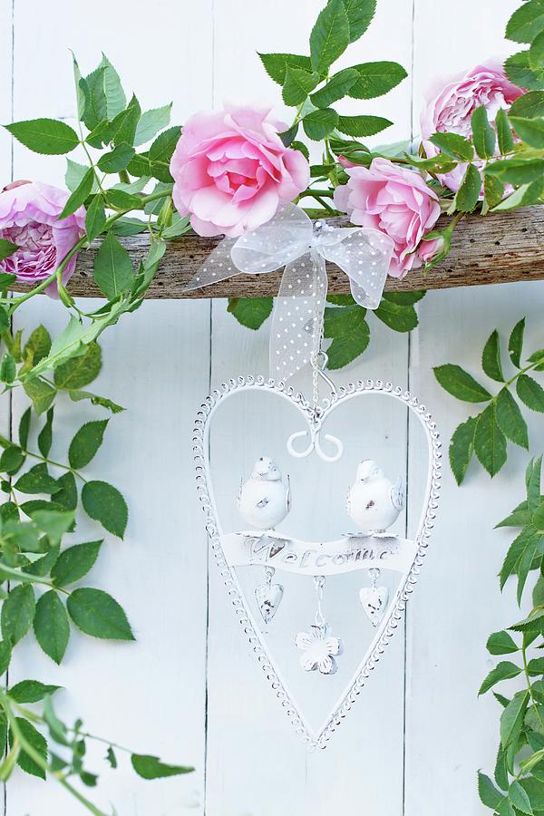 Heart-shaped, Ornate Metal Welcome Sign Hanging From Branch Decorated With Garland Of Roses Photograph by Angelica Linnhoff