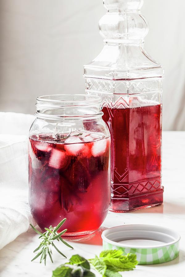 Hibiscus Iced Tea In A Screw Top Glass Jar And A Decorative Glass Bottle Photograph by Susan Brooks-dammann