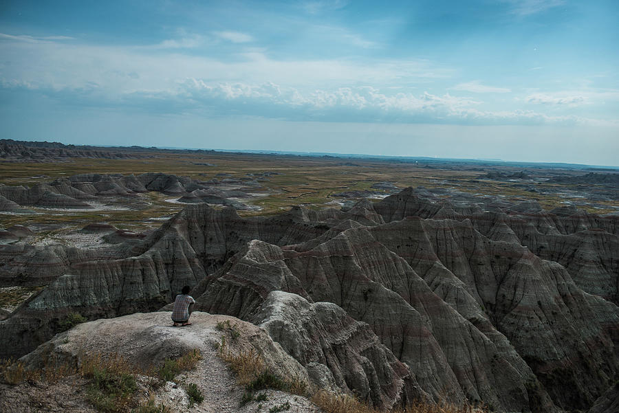 Badlands National Park Photograph - High Angle View Of Hiker Crouching On Rocks At Badlands National Park Against Sky by Cavan Images