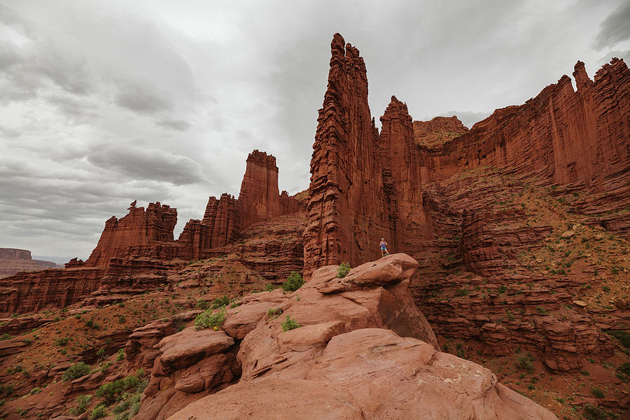 Desert Photograph - Hiking At Fisher Towers Under Cloudy Skies Near Moab Utah by Cavan Images