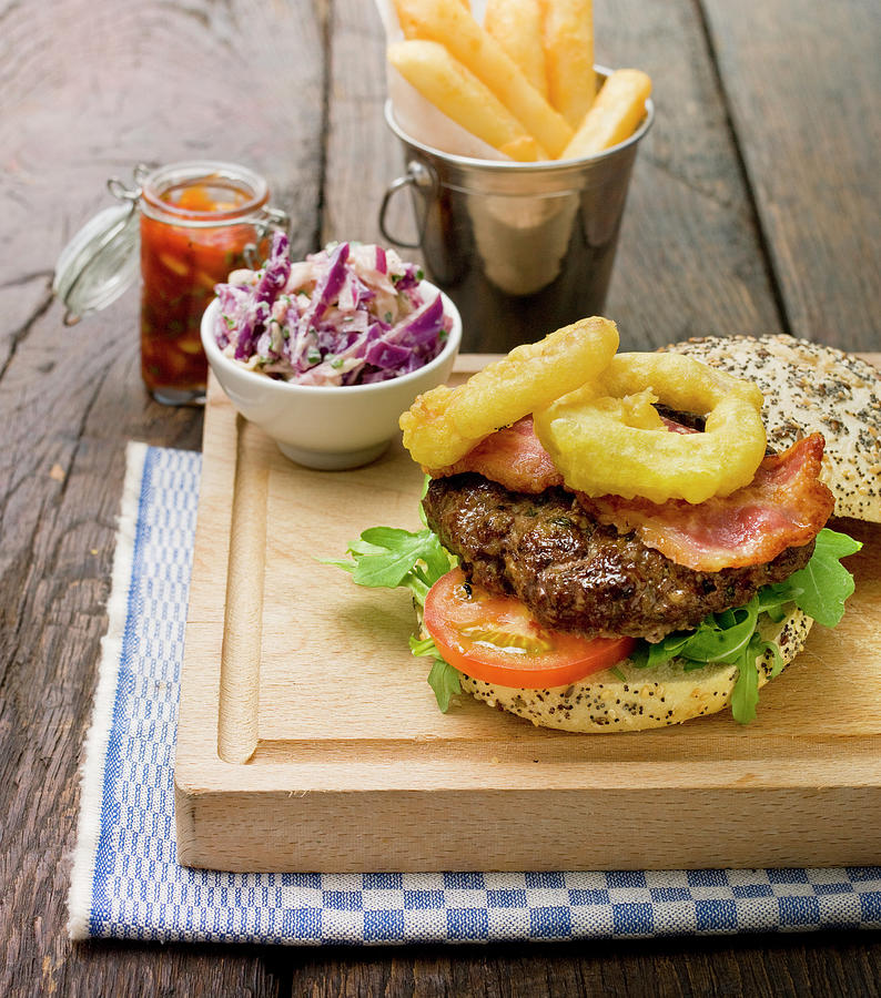 Home Made Burger With Rocket Lettuce, Tomato, Bacon And Onion Rings In A Sesame Seed Bun Photograph by Clive Sherlock