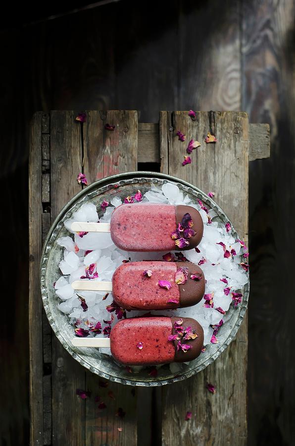 Homemade Cherry And Rose Mangnums With A Drak Chocolate Tip, On A Dark Wooden Background Photograph by Donna Crous