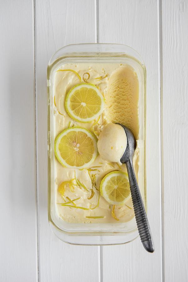 Homemade Lemon Ice Cream In A Glass Tub With Ice Cream Scoop, View From Above Photograph by Magdalena Hendey