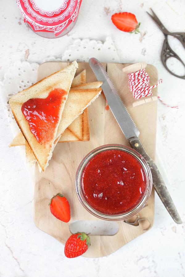 Homemade Strawberry Jam In A Jar And On Triangles Of Toast Photograph by Claudia Gargioni