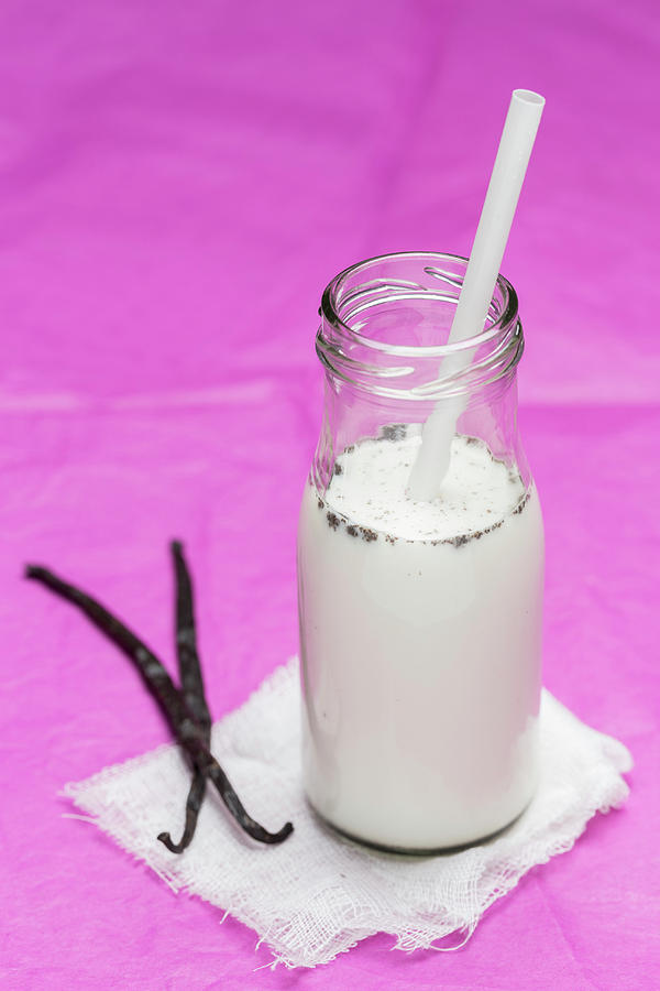 Homemade Vanilla Milk In A Glass Bottle Against A Pink Background Photograph by Nils Melzer