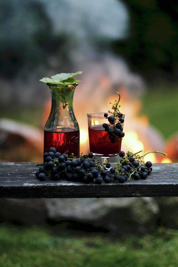 Homemade Wine And Red Grapes With A Campfire In The Background ...