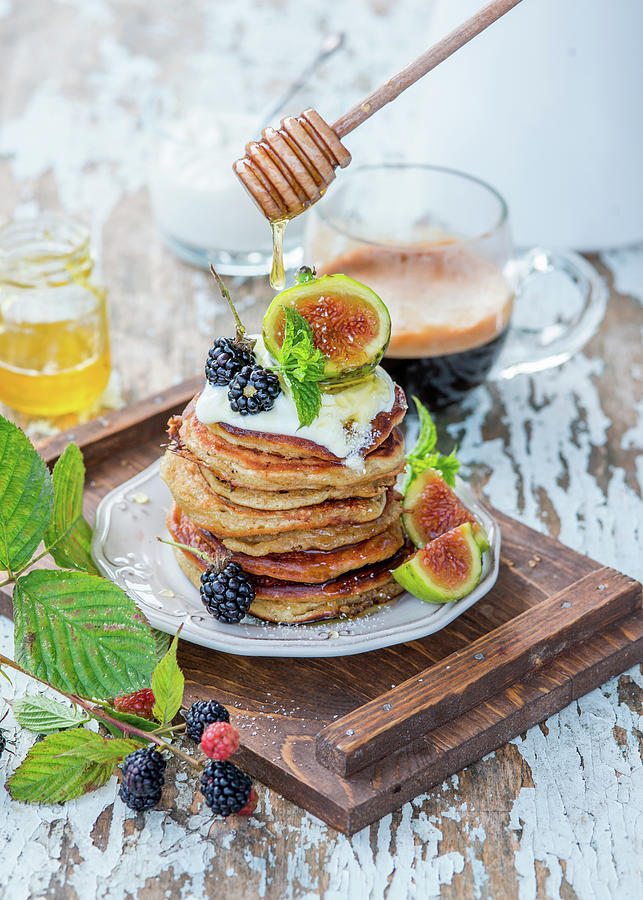 Honey Being Drizzled Over A Stack Of Pancakes With Yoghurt, Figs And Blackberries Photograph by Irina Meliukh