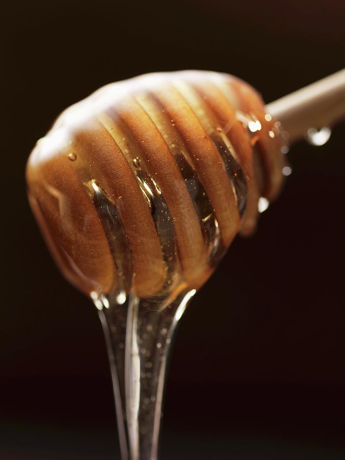 Honey Dripping From A Honey Dipper Photograph by Foodcollection