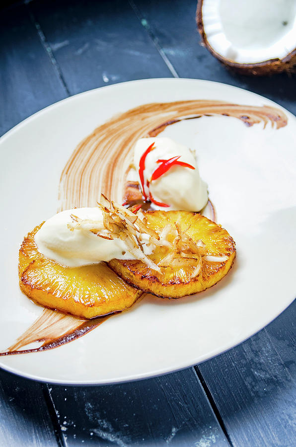 Honey Glazed Grilled Pinapple With Coconut Sorbet Ice Cream, Essiccated Coconut Flakes And Chilli On A White Plate And Blue Table Photograph by Giulia Verdinelli Photography