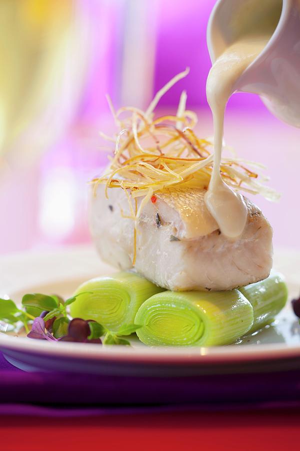 Horseradish Sauce Being Poured Over Cod Fillet On Leeks Photograph by Studio Lipov