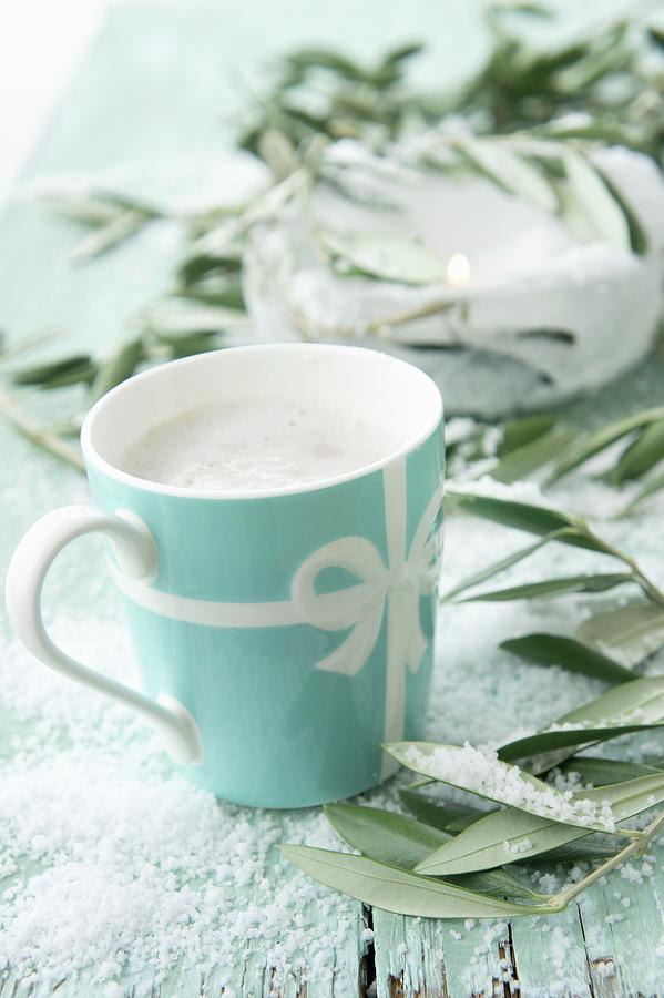 Hot Chocolate With Milk Foam Between Olives Sprigs On A Table Covered With Snow Photograph by Martina Schindler