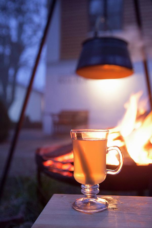 Hot Drink In Glass Mug In Front Of Fire In Brazier In Garden Photograph by Anneliese Kompatscher