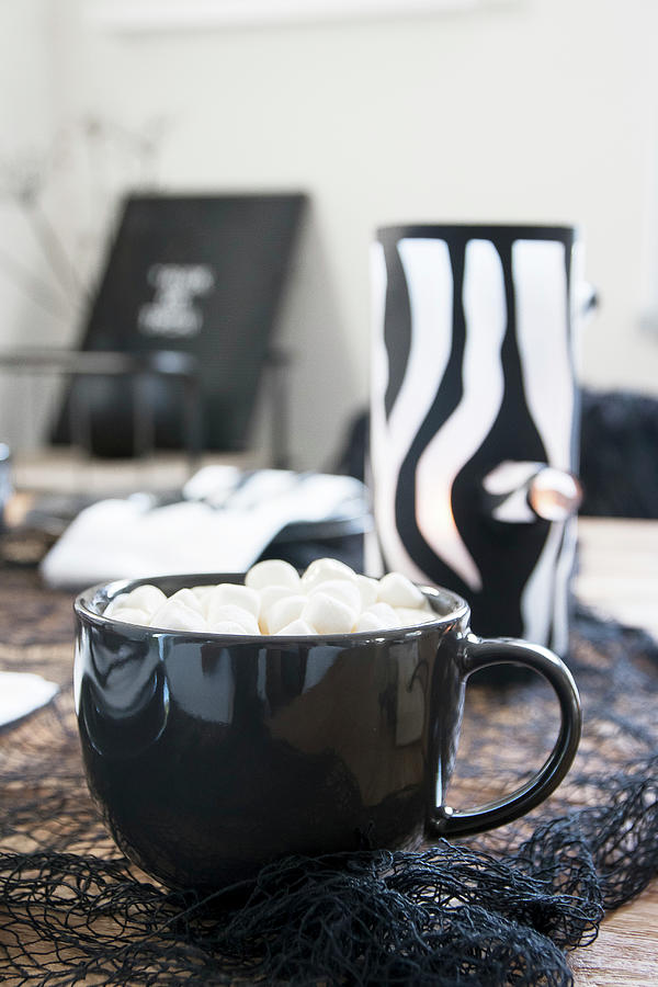 Hot Drink Topped With Marshmallows In Black Cup In Front Of Handmade Tealight Holder Photograph by Astrid Algermissen