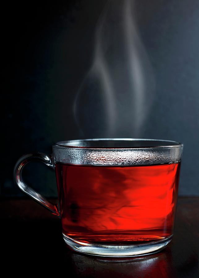 Hot Red Berry Fruit Tea In A Glass Mug With Steam Standing On A Dark Wood With Dark Grey Background Photograph by Etienne Voss