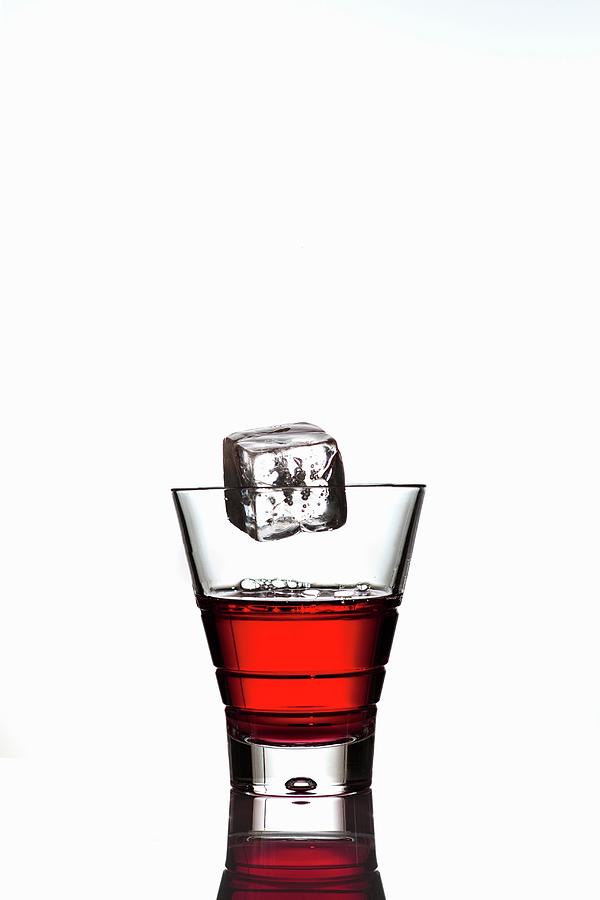 Ice Cube Falling Into A Glass Of Campari Photograph by Feig & Feig
