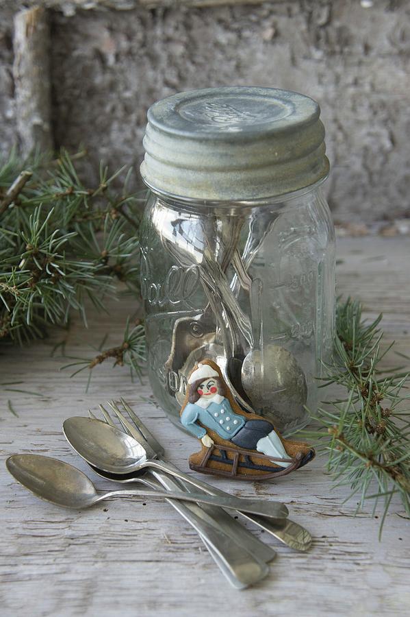 Iced Biscuit Shaped Like Boy On Sledge Leaning Against Screw-top Jar Holding Silver Cutlery Photograph by Martina Schindler