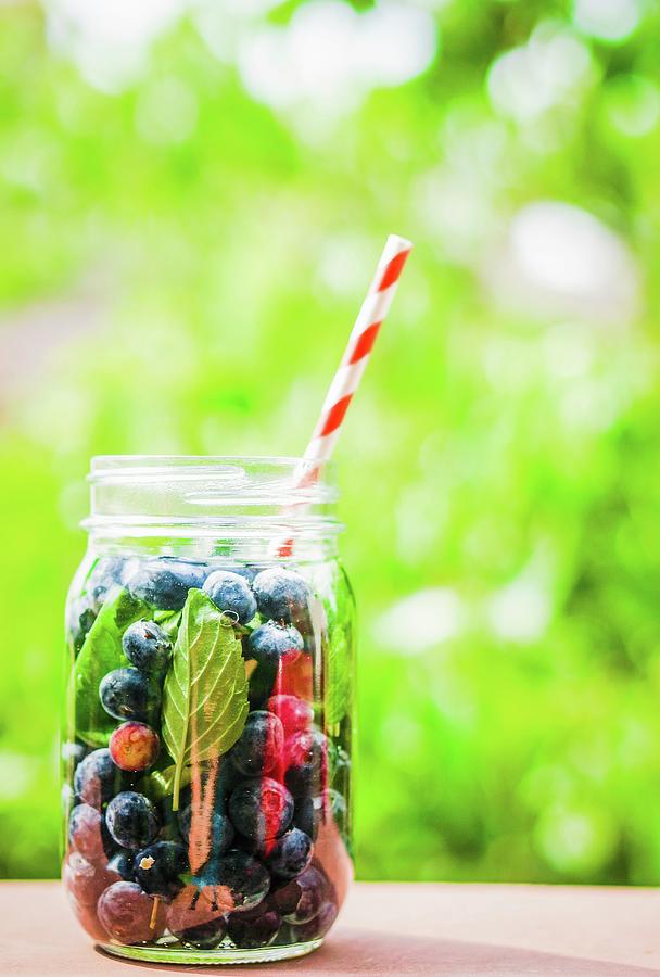 Iced Tea With Blueberries In A Screw-top Jar With A Straw On A Garden Table Photograph by Alena Haurylik