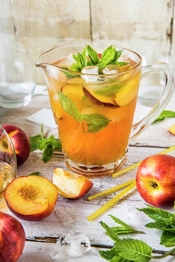 Iced Tea With Nectarines And Mint In A Glass Jug Photograph by Magdalena Hendey