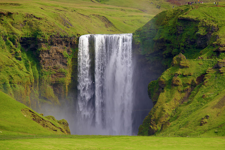Premium Photo  A rock formation appears to gaze in silence at the imposing  skogafoss waterfall during an evening icelandic summer