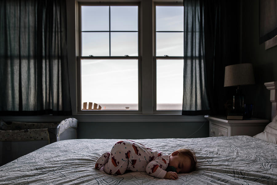 Beach Photograph - Infant Sleeping On Bed With View Of The Ocean Outside The Window by Cavan Images