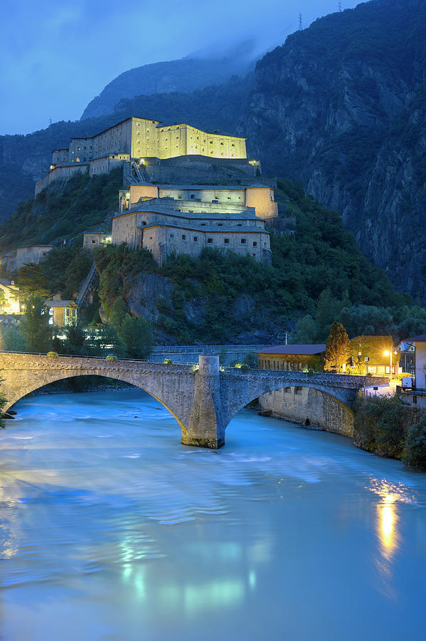Italy, Aosta Valley, Aosta District, Alps, Bard, The Roman Bridge And The Castle At Dusk Digital Art by Franco Cogoli