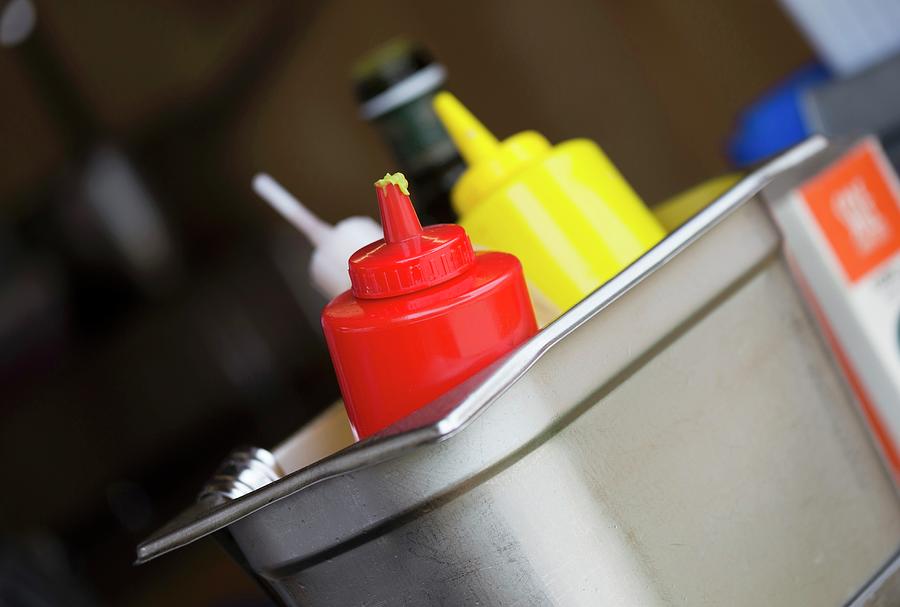 Ketchup, Mustard And Seasoning Sauces In A Metal Container In A Restaurant Photograph by Adel Bekefi