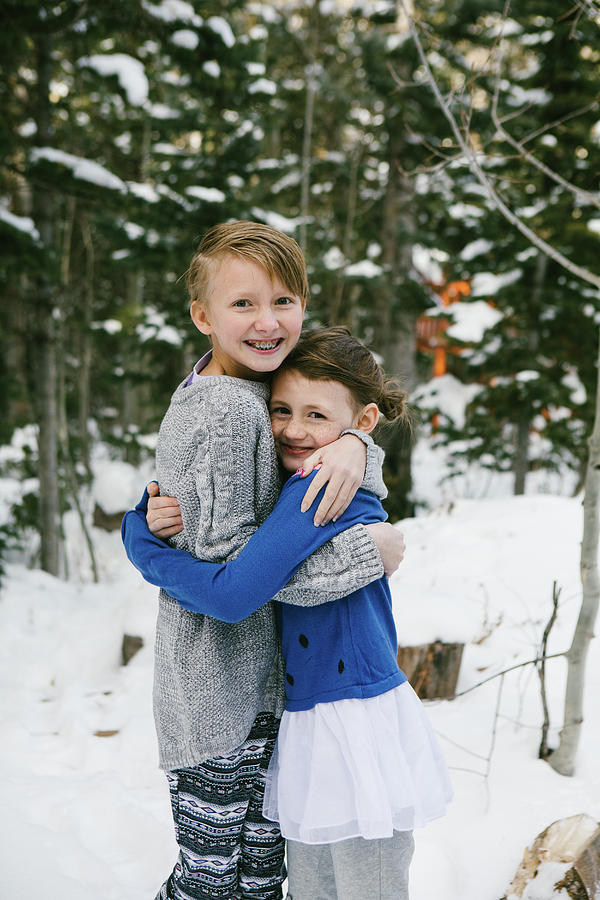 Nature Photograph - Kids Hug In Snow Covered Forest In Sweaters And Warm Clothes by Cavan Images / Anna Rasmussen Photographs
