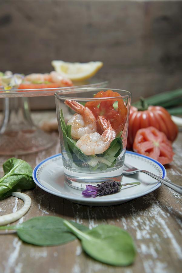 King Prawns On A Spinach Salad In A Glass With Beefsteak Tomatoes, Spring Onions And Lemons In The Background Photograph by Angelika Grossmann