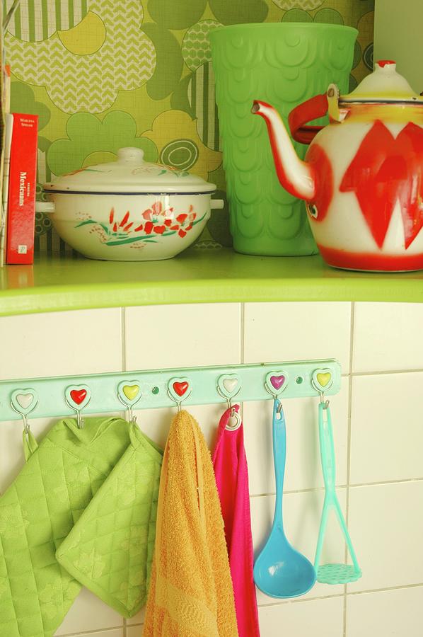 Kitchen Utensils Hanging From Wall Hooks Under Green-painted Shelf Holding Enamel Teapot And Pan Photograph by James Stokes
