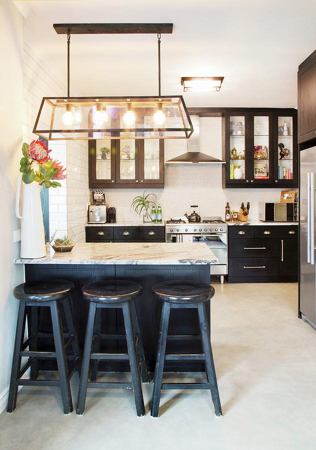 Kitchen With Black Cupboards And Bar Stools Next To Counter With Marble Top Photograph by Great Stock!
