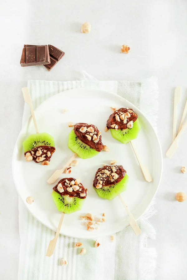 Kiwi Lollipops With Melted Chocolate And Chopped Hazelnuts Photograph by Claudia Gargioni