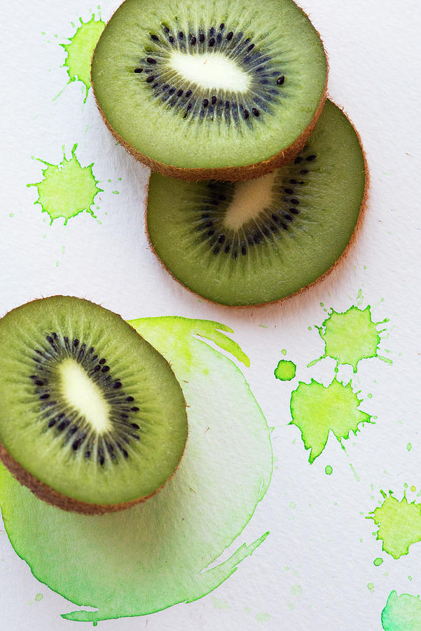 Kiwi Slices On A Paper Background With Green Splashes Of Colour Photograph by Stacy Grant
