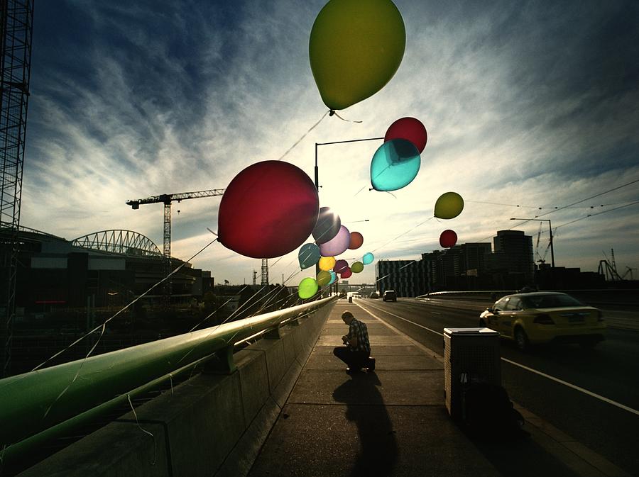 Kneeling Figure On Bridge With Balloons Photograph by Jesse Swallow
