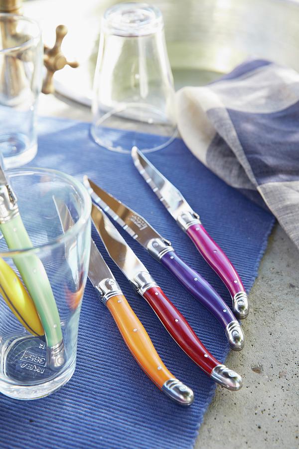 Knives With Coloured Handles Of A Placemat Photograph by Jalag / Olaf Szczepaniak