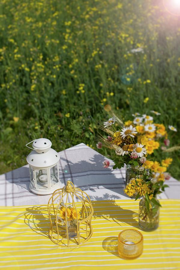 Lantern, Ornamental Birdcage And Posies Of Wildflowers On Yellow And White Striped Tablecloth Outdoors Photograph by Annette Nordstrom