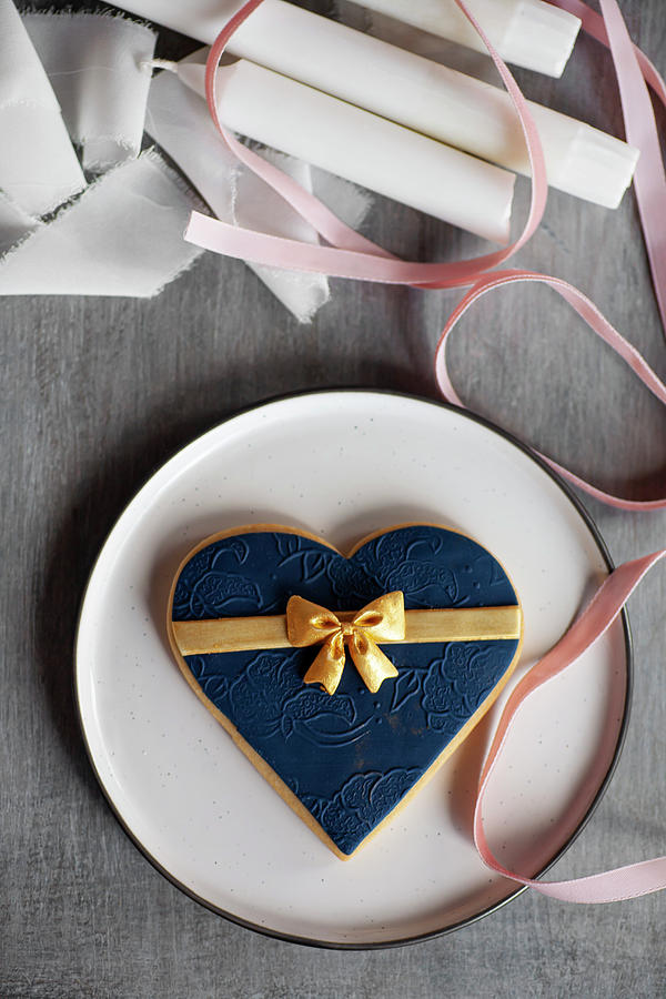 Large Heart-shaped Biscuit With Blue Fondant Icing And Golden Bow Photograph by Alicja Koll