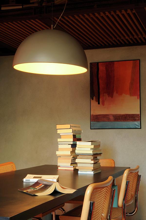Large Hemispherical Lamp Above Stacked Books On Dining Table Photograph by Michele Mulas