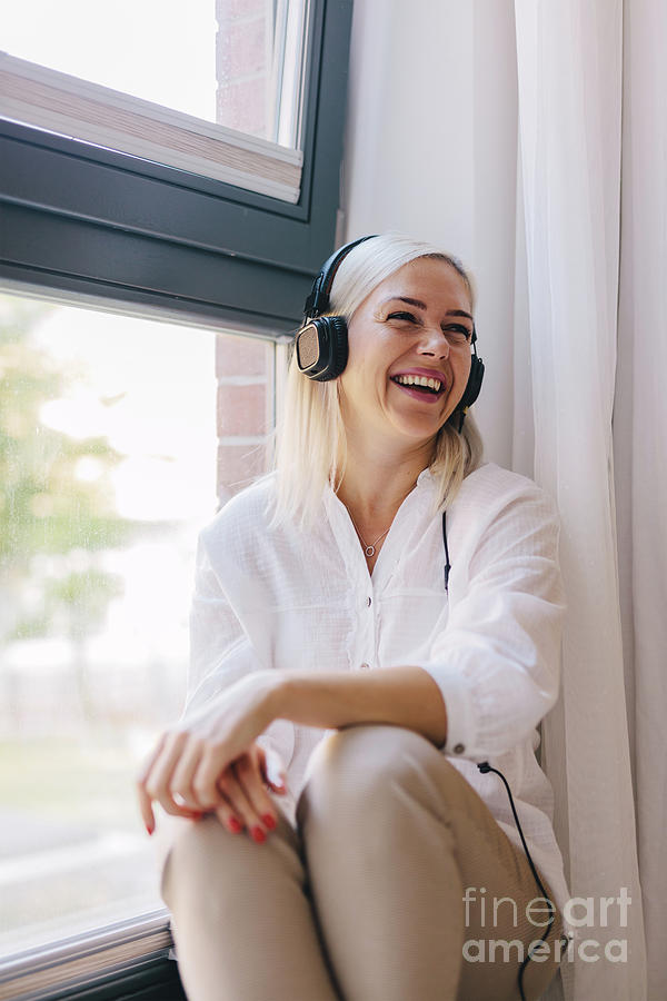 Laughing woman listening to music on headphones. Photograph by Michal Bednarek