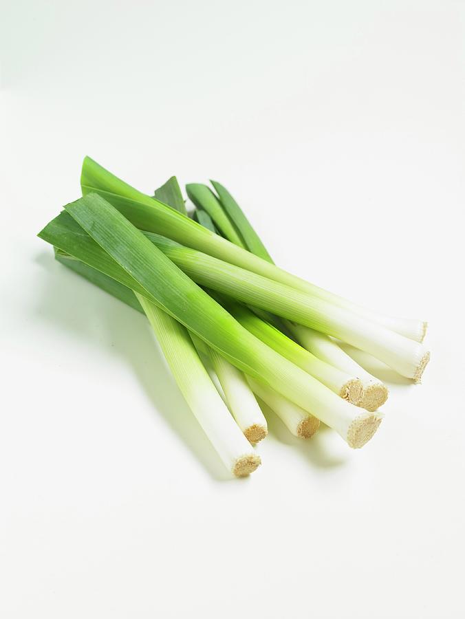 Leeks On A White Surface Photograph by Alex Luck
