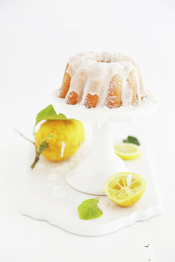 Lemon Bundt Cake With Light Icing On A White Cake Stand Photograph by Syl Loves