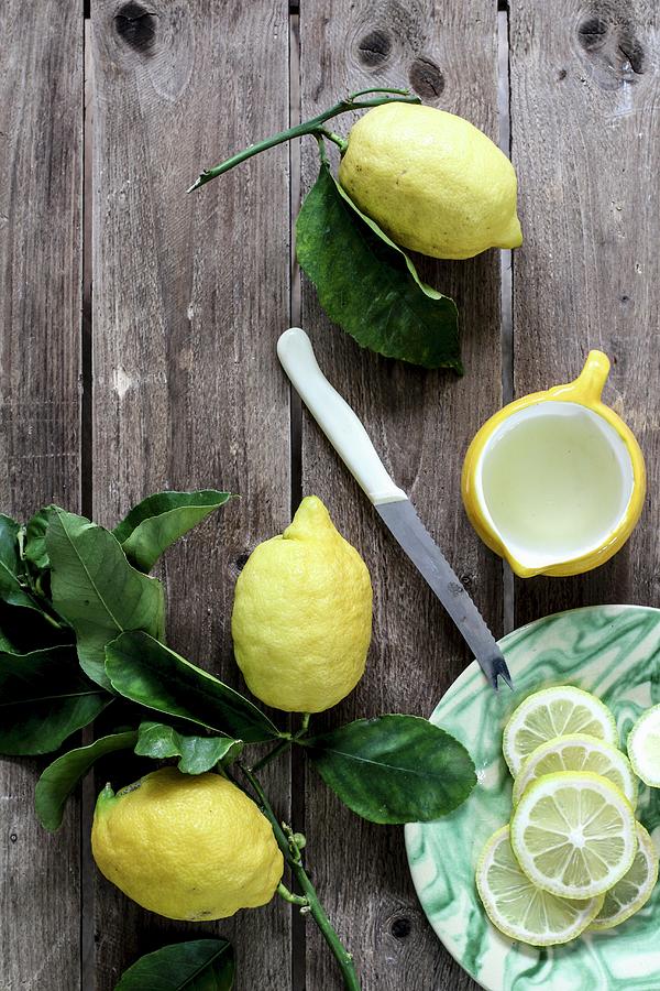 Lemons, Whole And Sliced, On A Wooden Background Photograph by Dees Kche