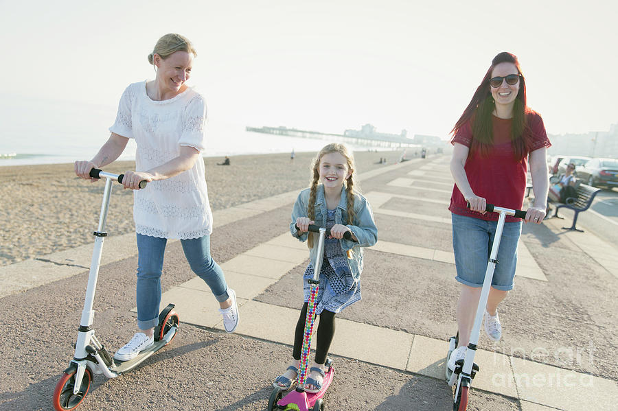 Lesbian Couple And Daughter Riding Push Scooters Photograph By Caia