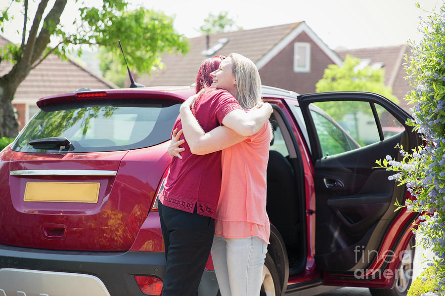 Lesbian Couple Hugging By Car In Sunny Driveway Photograph By Caia