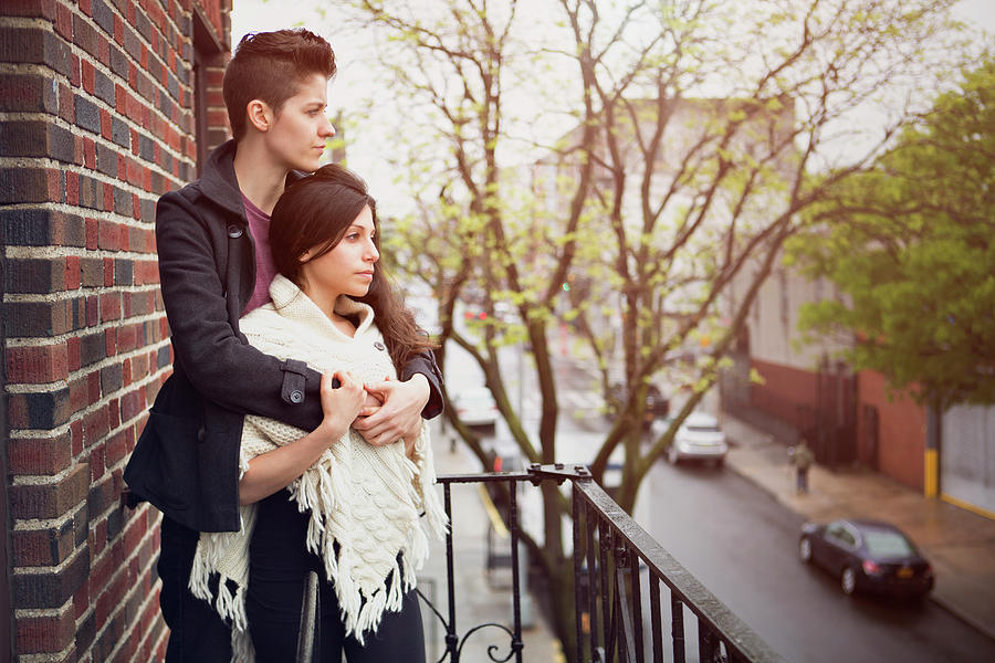 Lesbian Couple Looking Away While Standing In Balcony Photograph by ...