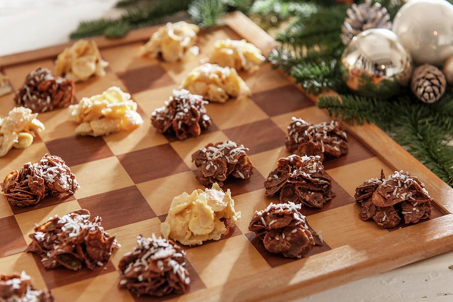 Light And Dark Cornflake Cakes On Chessboard Next To Christmas Decorations Photograph by Moog & Van Deelen