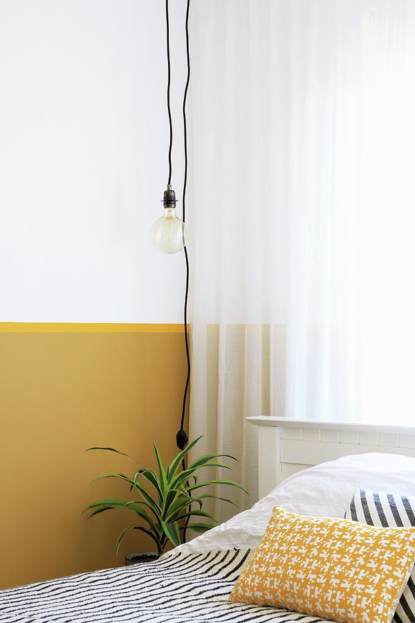 Light-bulb Pendant Lamp In Front Of Wall With Yellow Dado Photograph by Marij Hessel