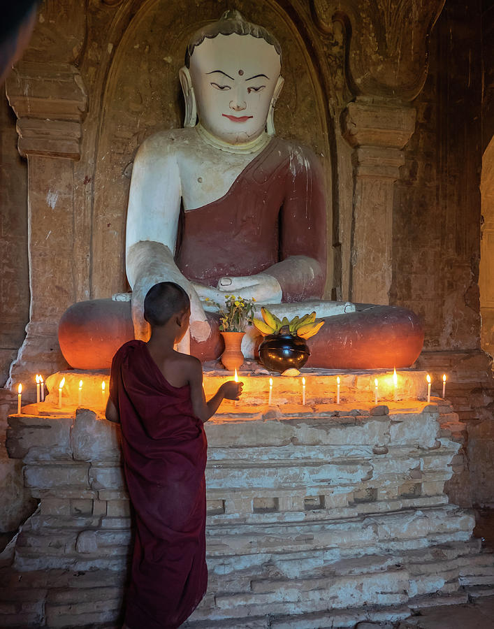 lighting candles at a statue of Buddha  Photograph by Ann Moore